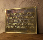 Memorial plaque for Cheryl Jennings on a wooden surface with a stone wall background